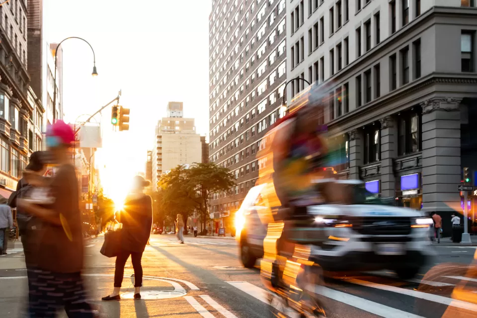Fast paced scene with people bike and cars at the busy intersection of 14th Street and 5th Avenue in New York City.